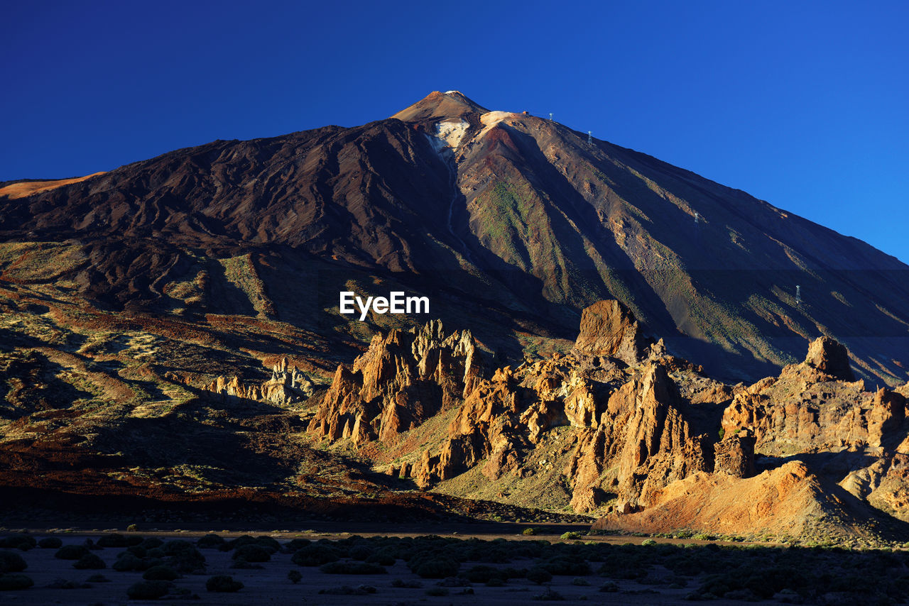 Scenic view of rocky mountains at el teide national park against clear blue sky