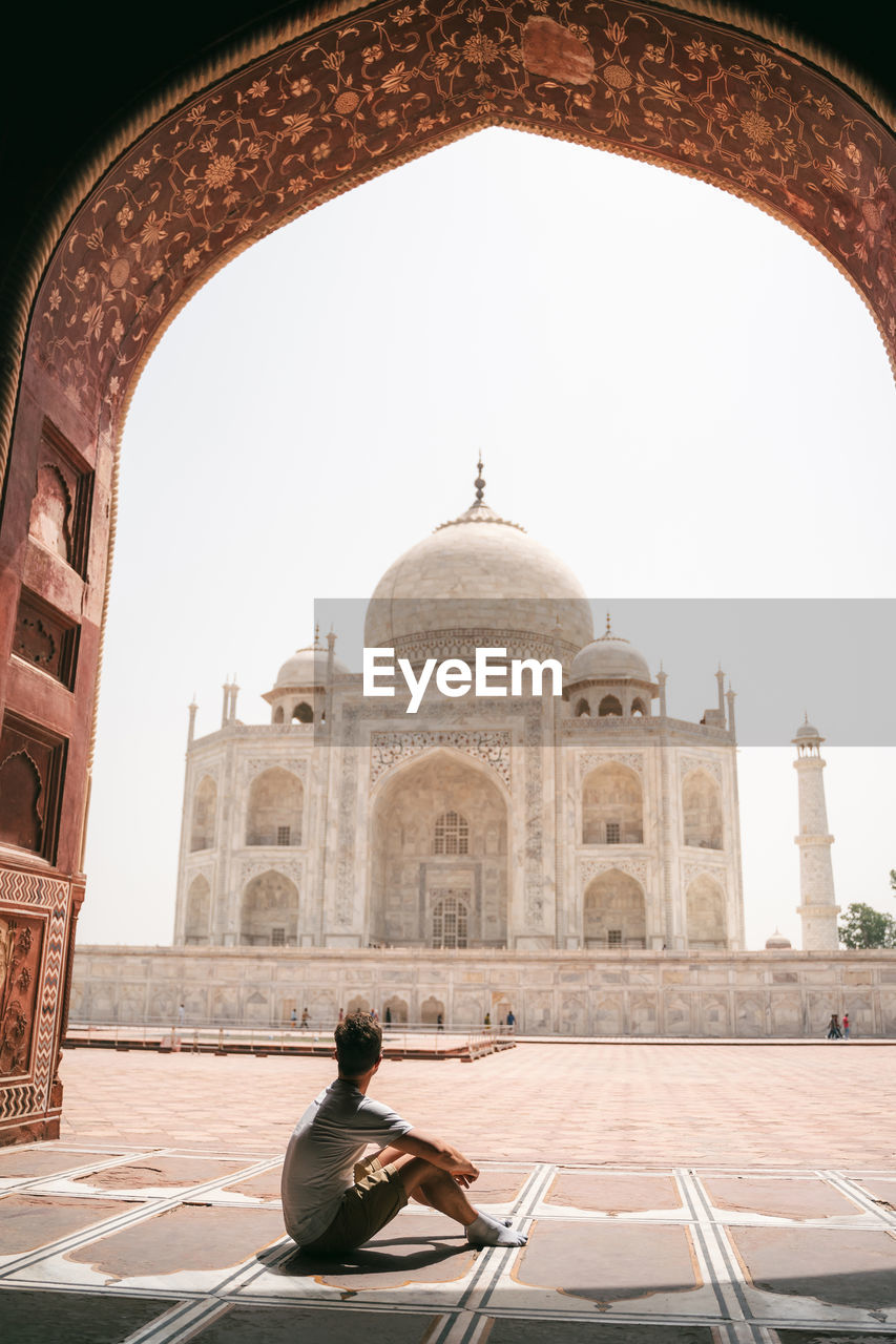 Full length of mans sitting against taj mahal