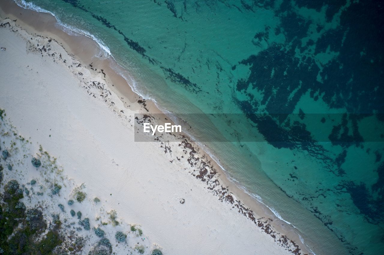 Drone field of view of of footprints in the sand and water from above beach in western australia.