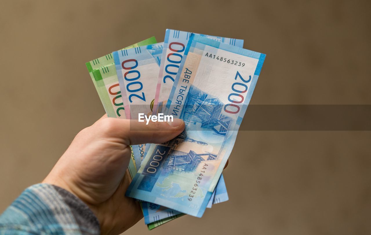 Close-up of man holding money against brown background