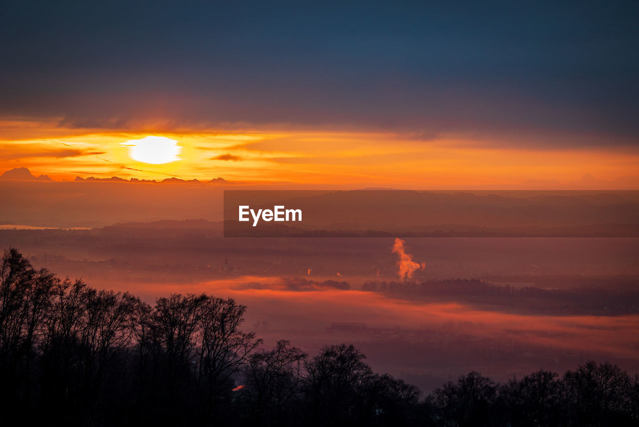 sky, sunset, beauty in nature, tree, cloud, scenics - nature, afterglow, environment, nature, tranquility, landscape, orange color, dawn, plant, red sky at morning, tranquil scene, silhouette, sun, dramatic sky, no people, horizon, idyllic, evening, land, forest, sunlight, outdoors, atmospheric mood, non-urban scene, fog, travel, travel destinations, mountain, cloudscape, multi colored, yellow, tourism, red, twilight, awe