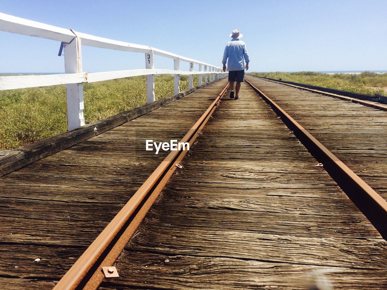 Rear view of man walking on railway bridge