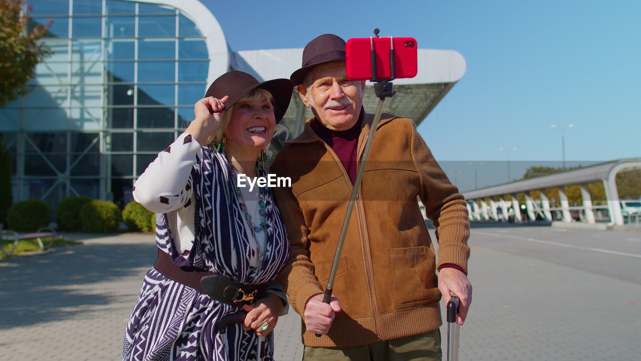 Smiling senior couple doing selfie standing outdoors