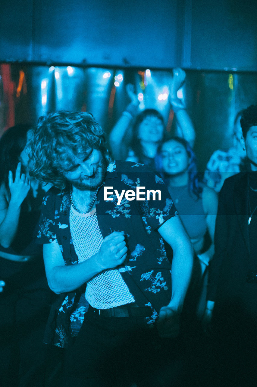 Cheerful multiracial male and female friends enjoying while dancing in club