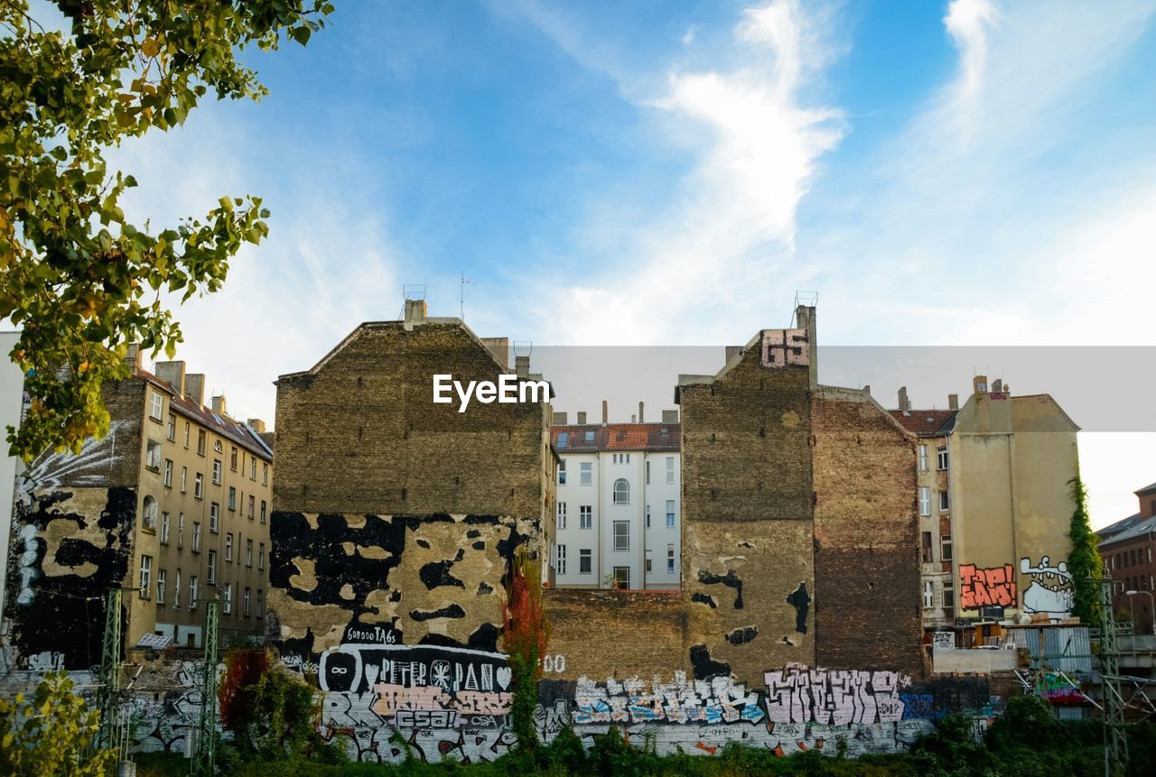 Graffiti on buildings against cloudy sky