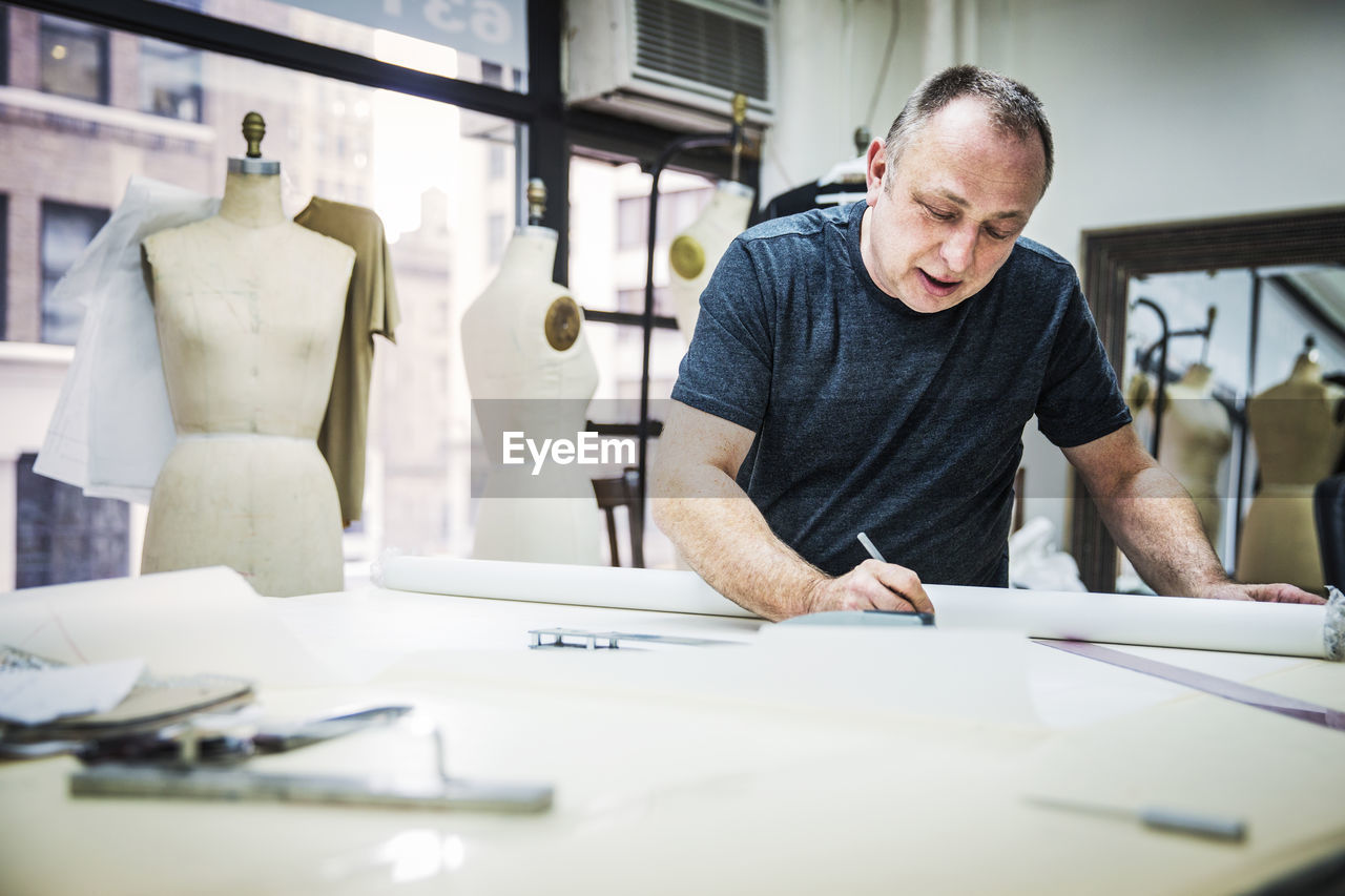 Serious fashion designer working at table in design studio