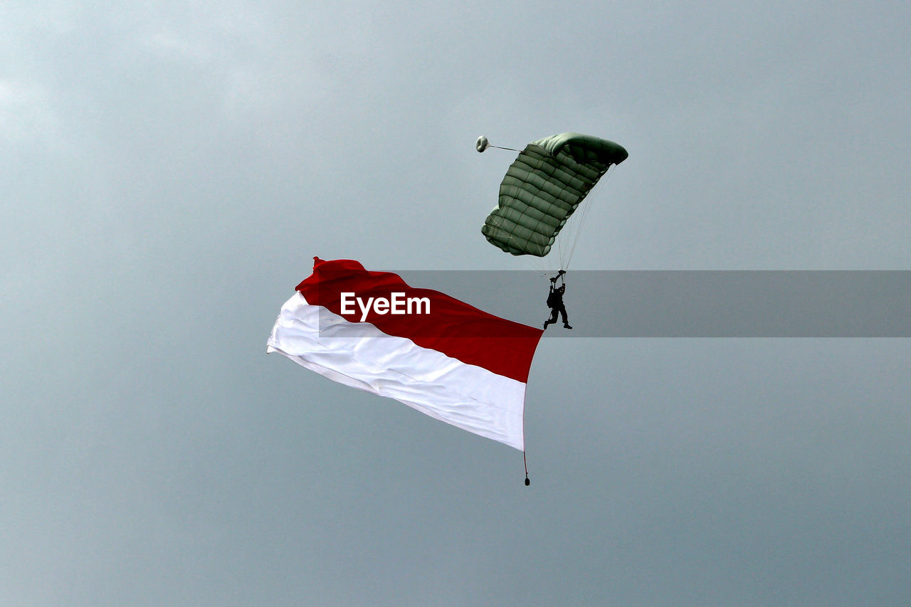 Low angle view of person paragliding against sky