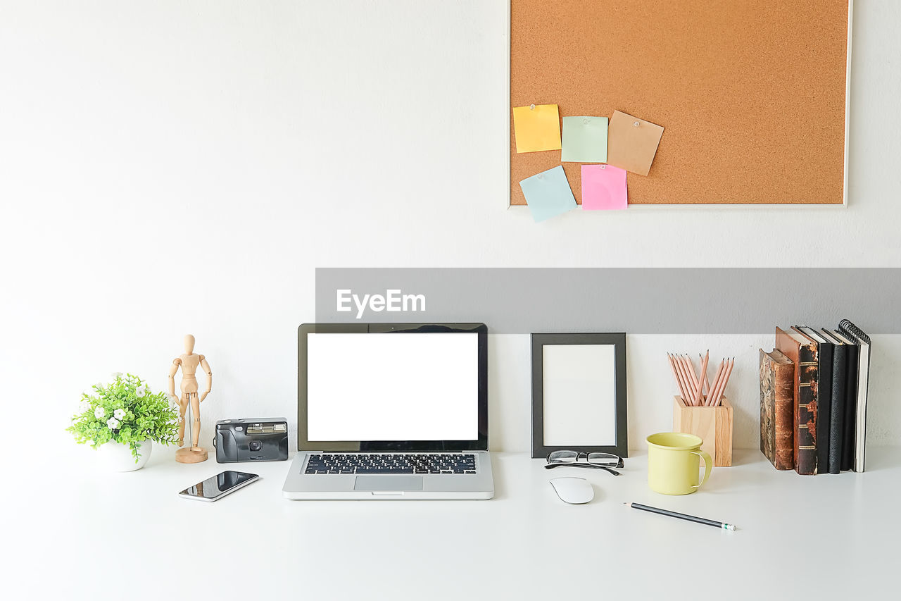 Close-up of technologies with books and wooden figurine on desk in office