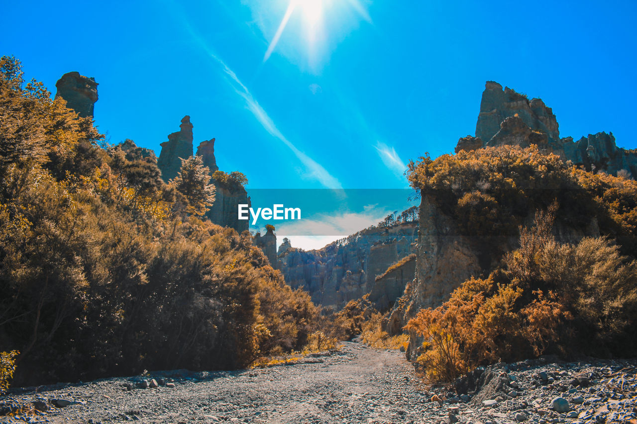 Scenic view of dirt road amidst rock formation against sky