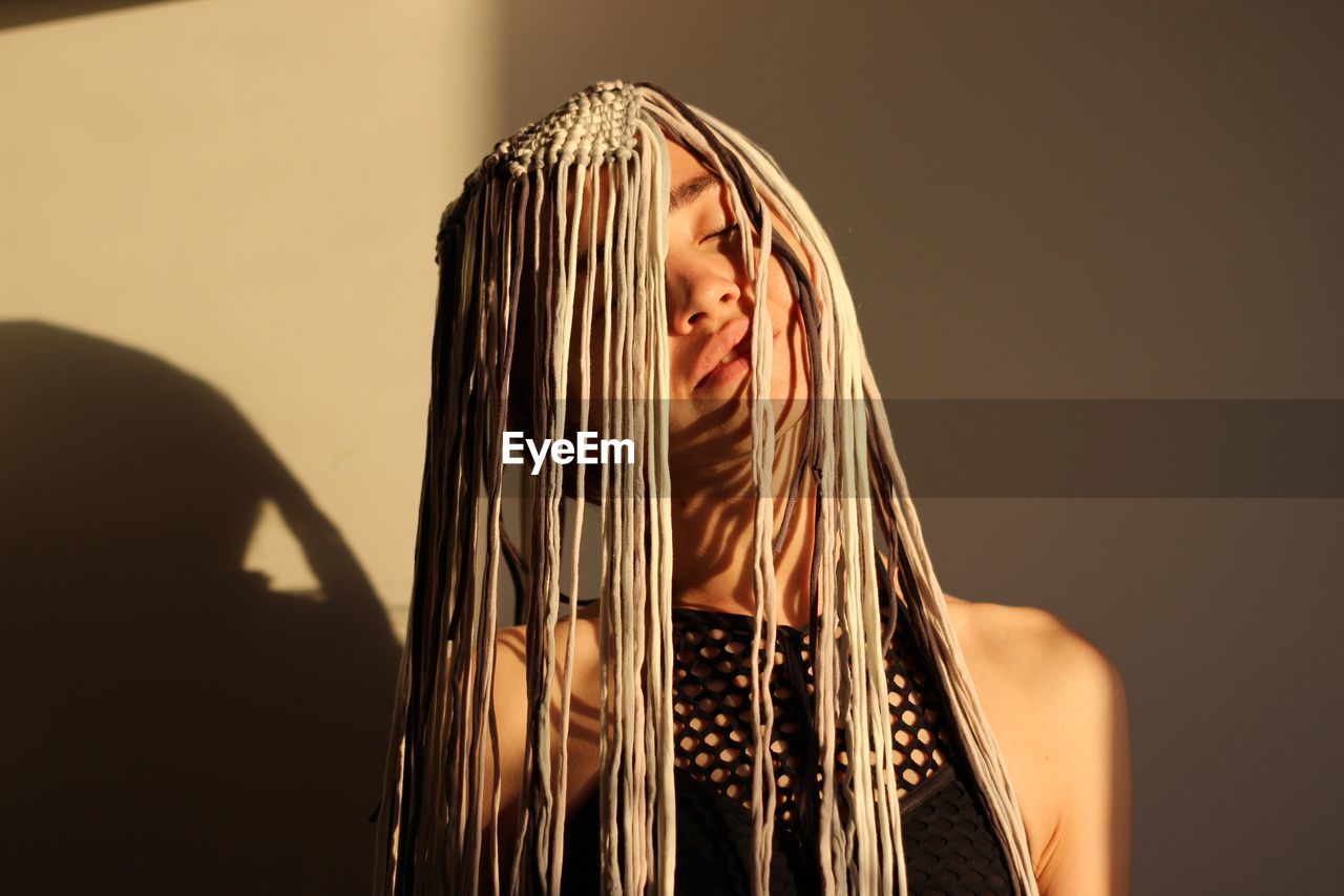 Close-up of woman wearing headwear by wall