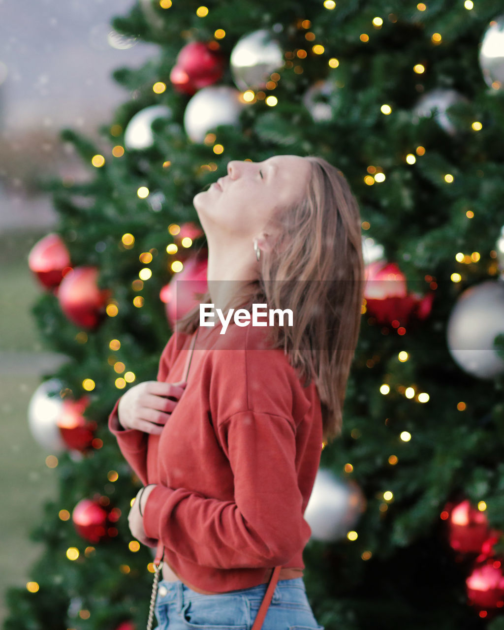 Side view of woman standing against christmas tree