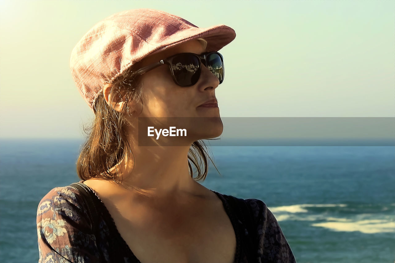 portrait of young woman wearing sunglasses against sea