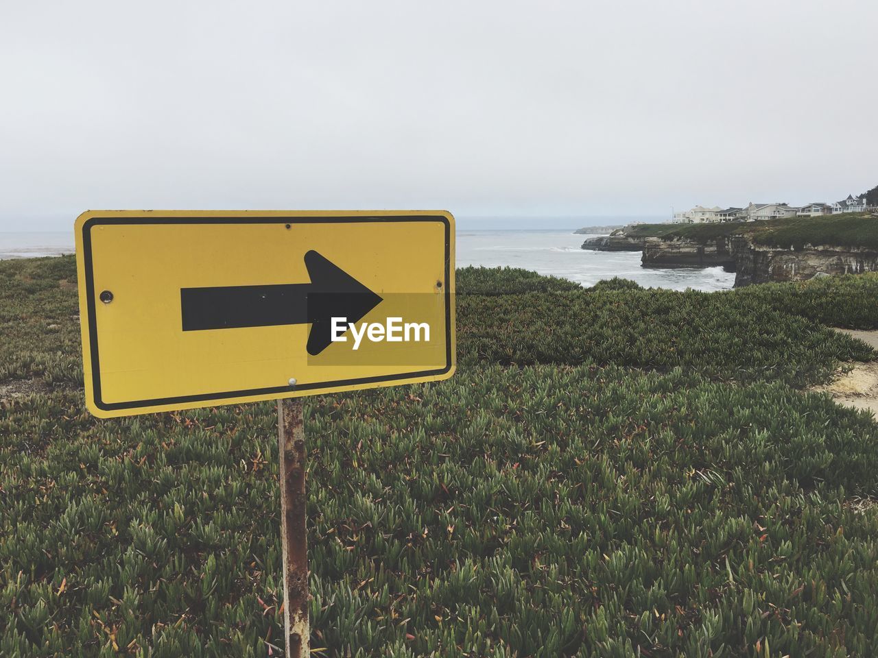 Directional sign at beach against sky