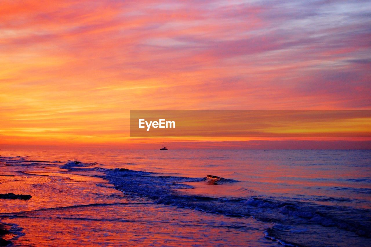 SCENIC VIEW OF BEACH AGAINST DRAMATIC SKY