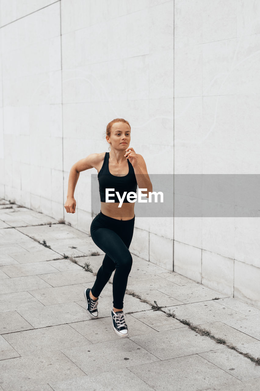 Full length of woman running against wall