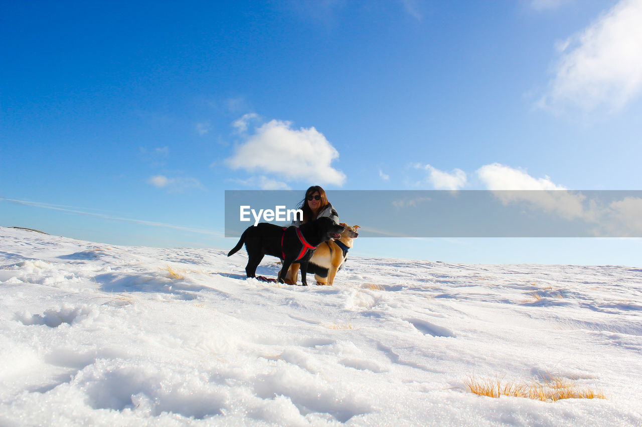 People with dog on snow against sky