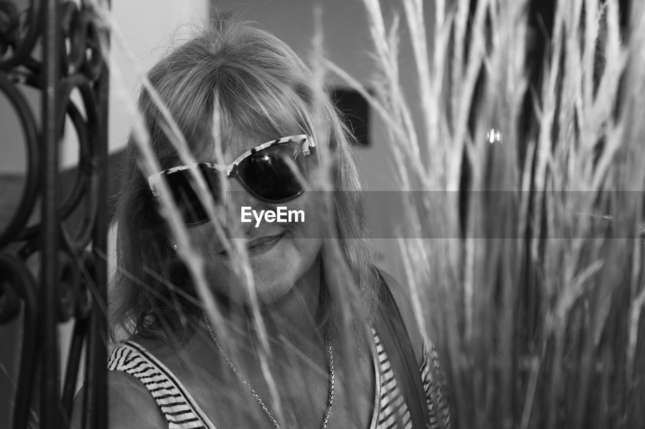 PORTRAIT OF YOUNG WOMAN WEARING SUNGLASSES OUTDOORS