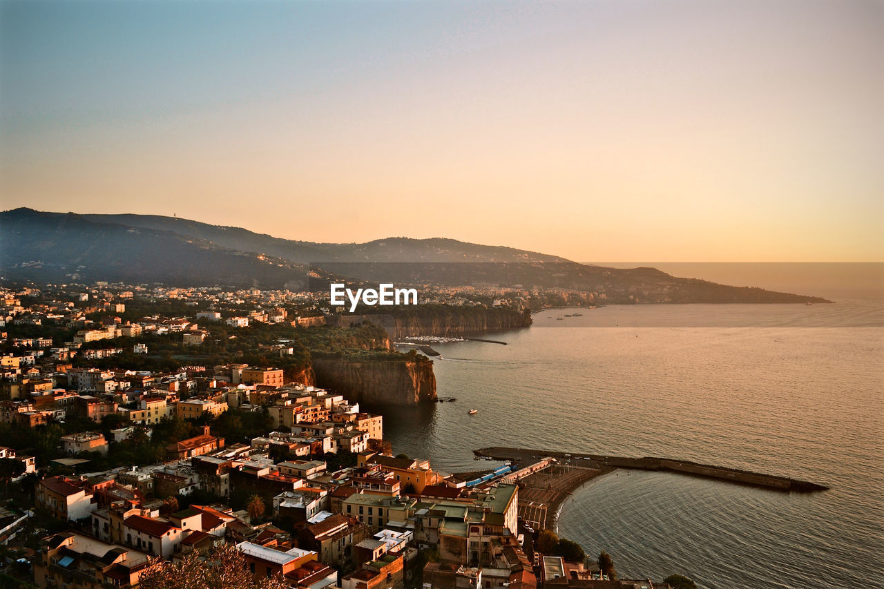 High angle view of townscape by sea against clear sky