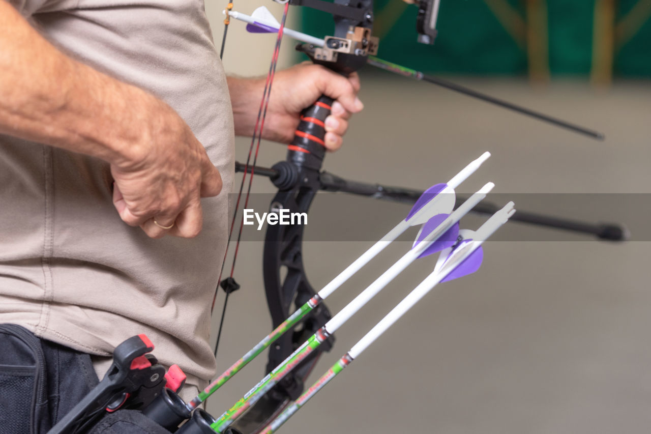 Midsection of man holding bow and arrow