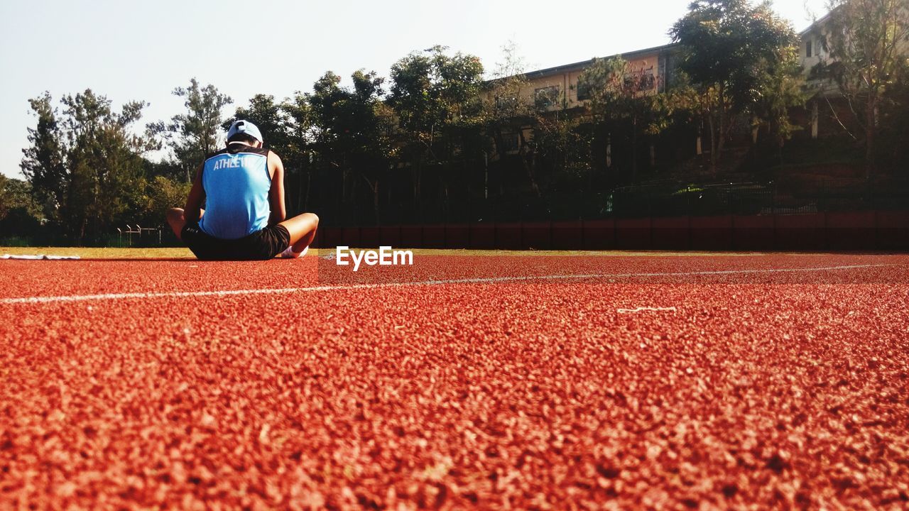 Rear view of athlete sitting on sports track