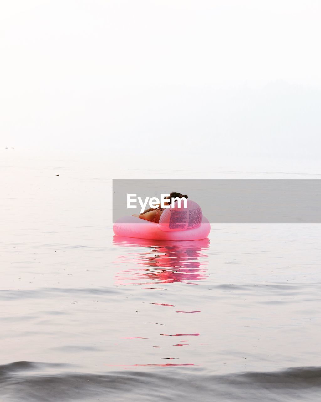 REAR VIEW OF COUPLE KISSING AGAINST SEA