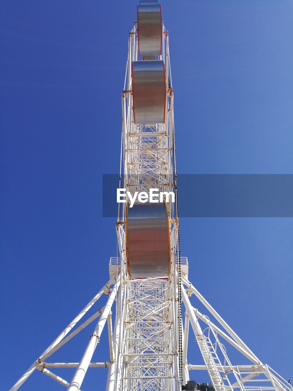 Directly below shot of ferris wheel against clear blue sky