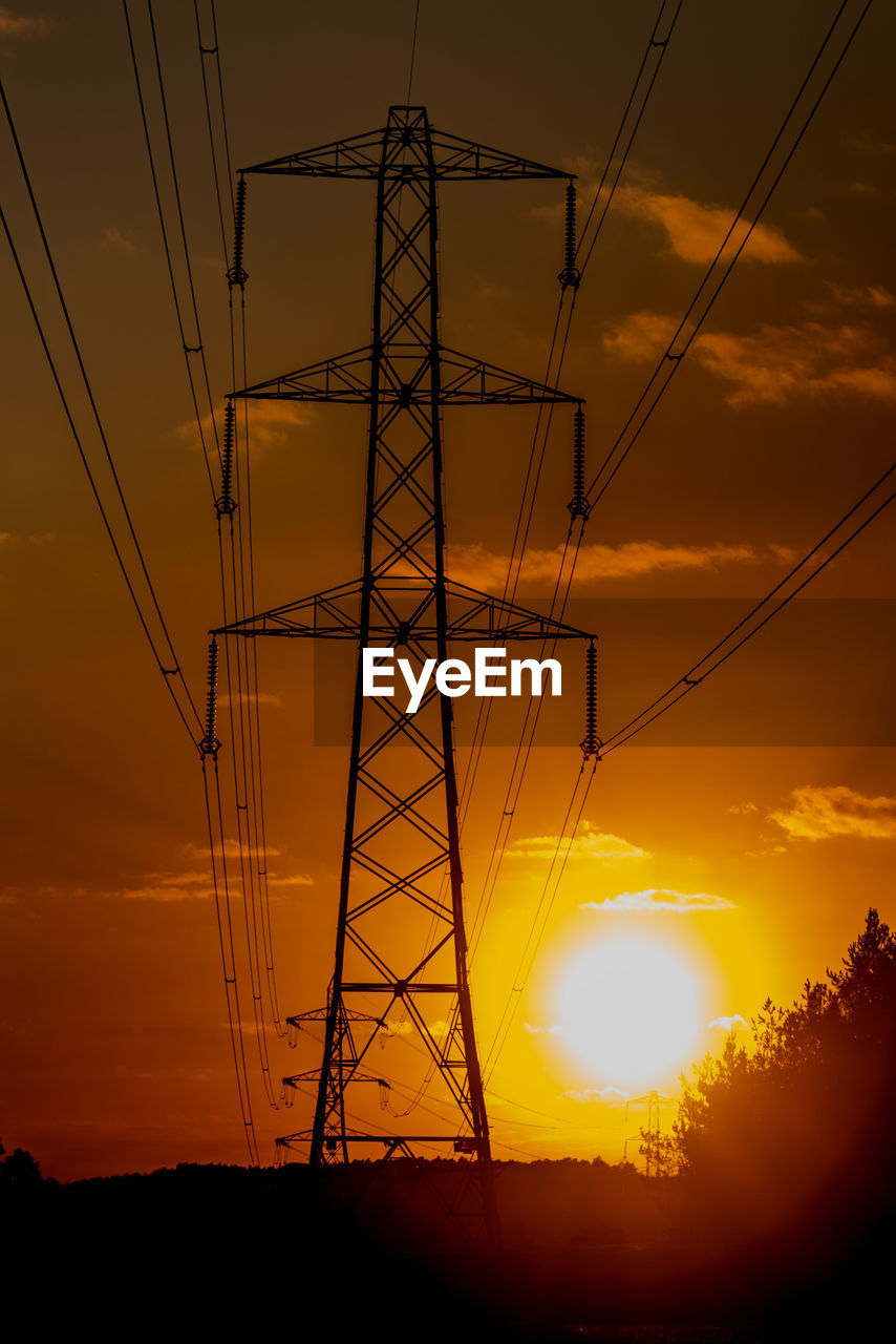 Low angle view of silhouette electricity pylon against sky during sunset