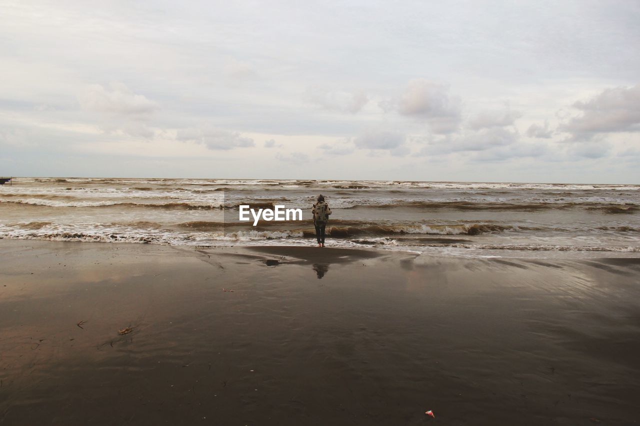 Rear view of woman standing at beach