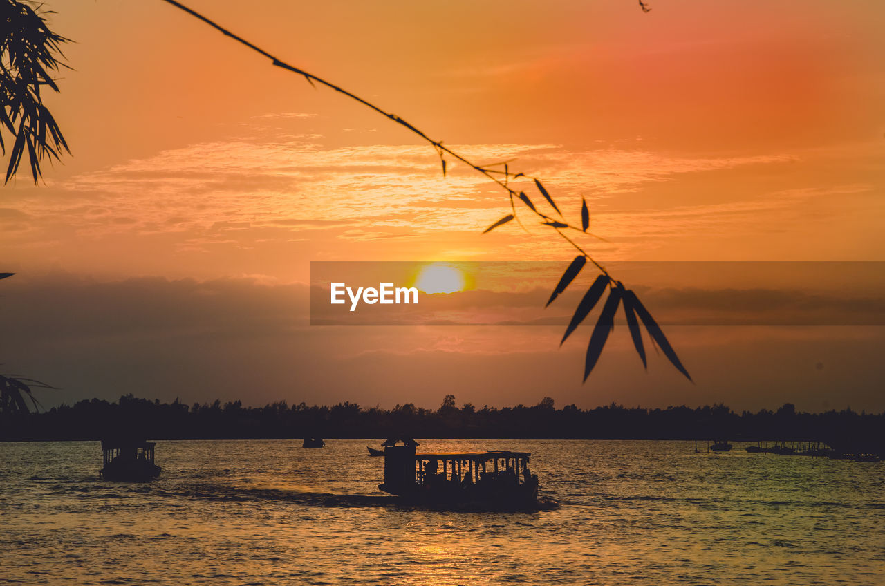 Silhouette boat on sea against orange sky