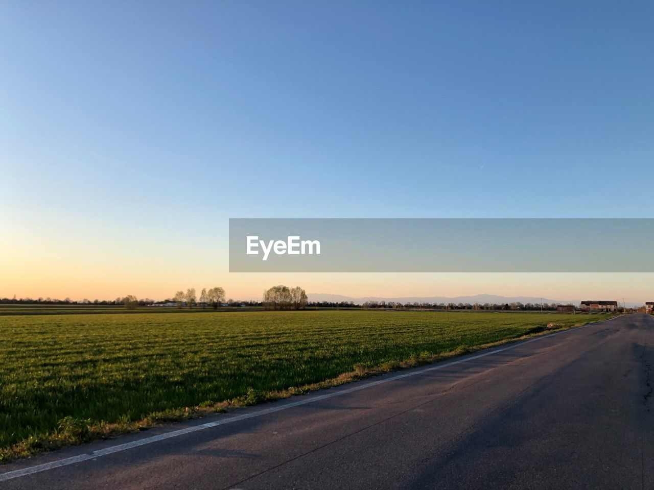 ROAD AMIDST FIELD AGAINST CLEAR SKY