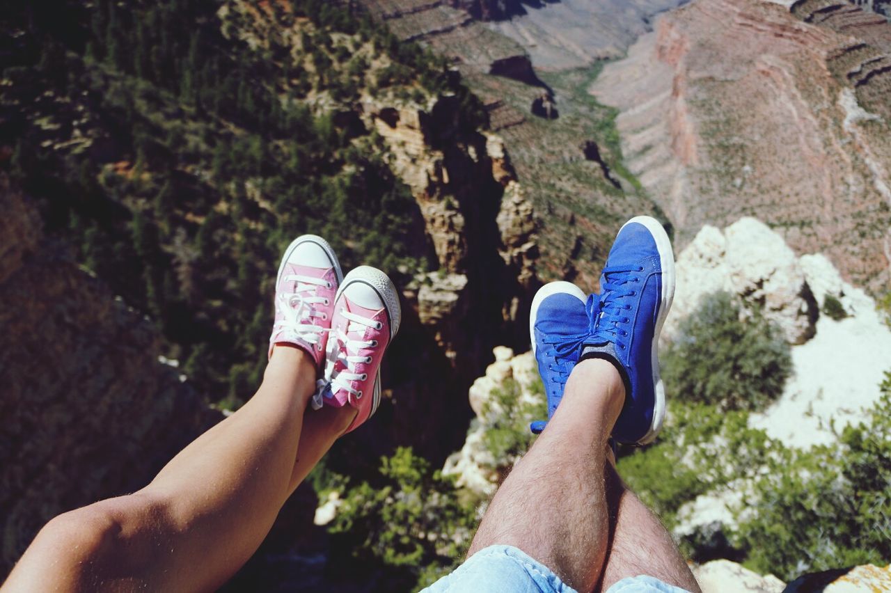 Midsection of woman and man wearing shoes over precipice