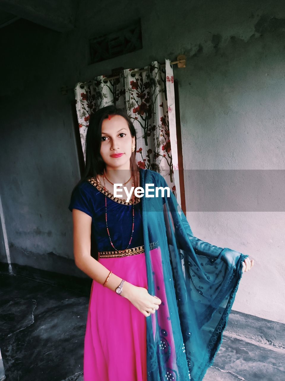 PORTRAIT OF BEAUTIFUL YOUNG WOMAN STANDING AGAINST THE WALL