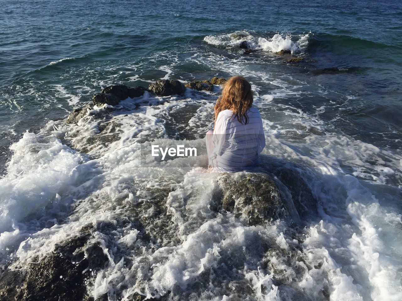 Rear view of young woman sitting at beach