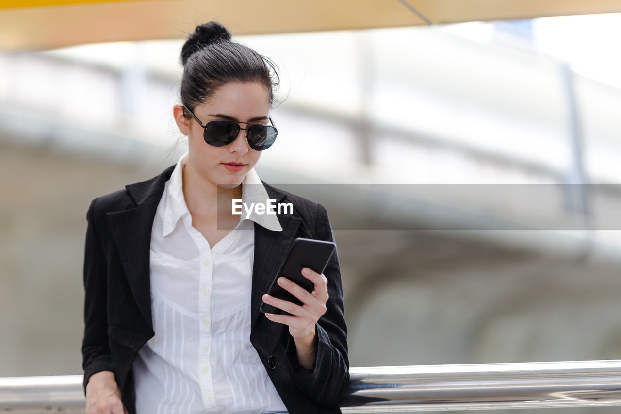 Young woman wearing blazer using phone