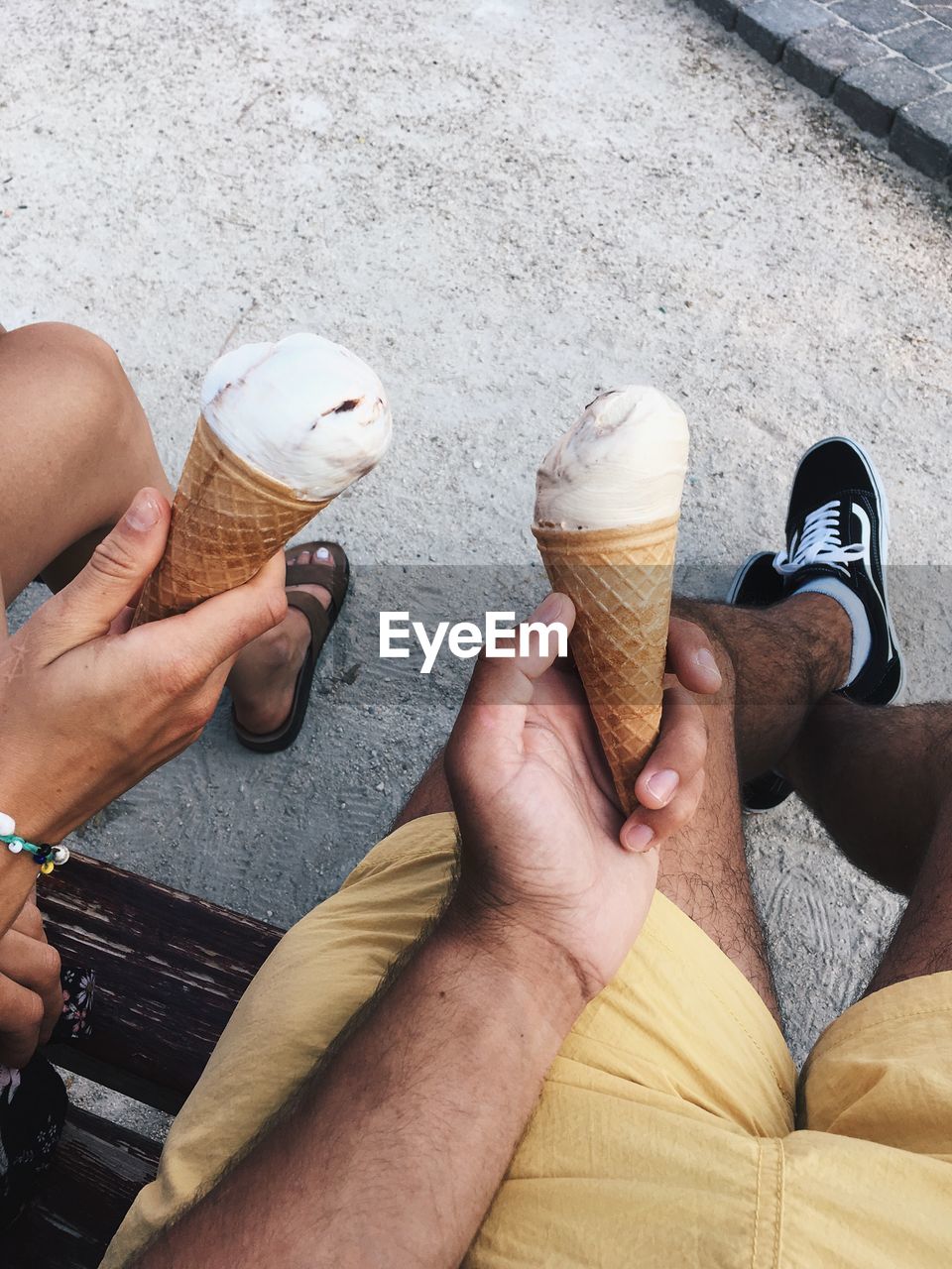 LOW SECTION OF PEOPLE HOLDING ICE CREAM OUTDOORS