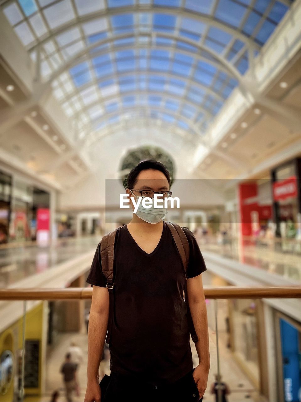 Portrait of young man standing against skylight and architecture 