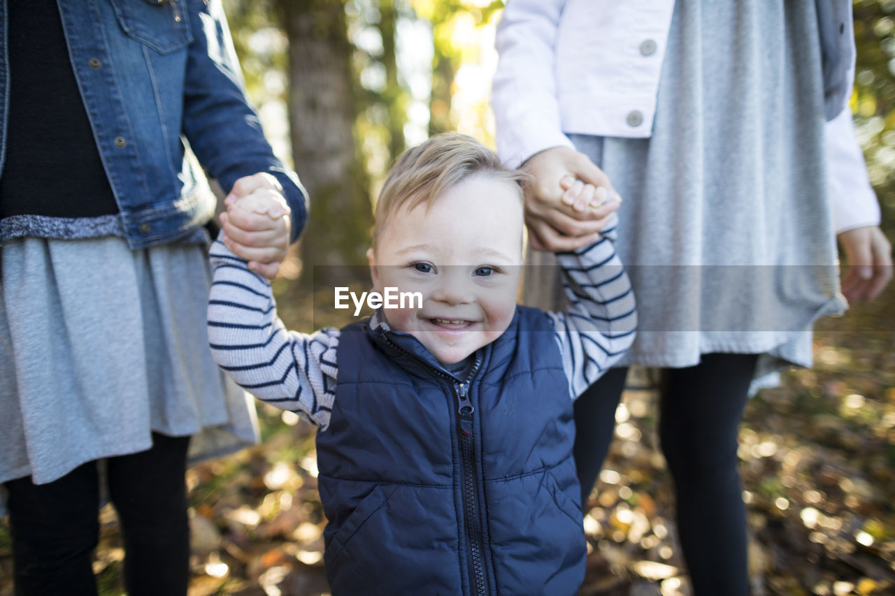 Midsection of girls holding sister hands while standing at park