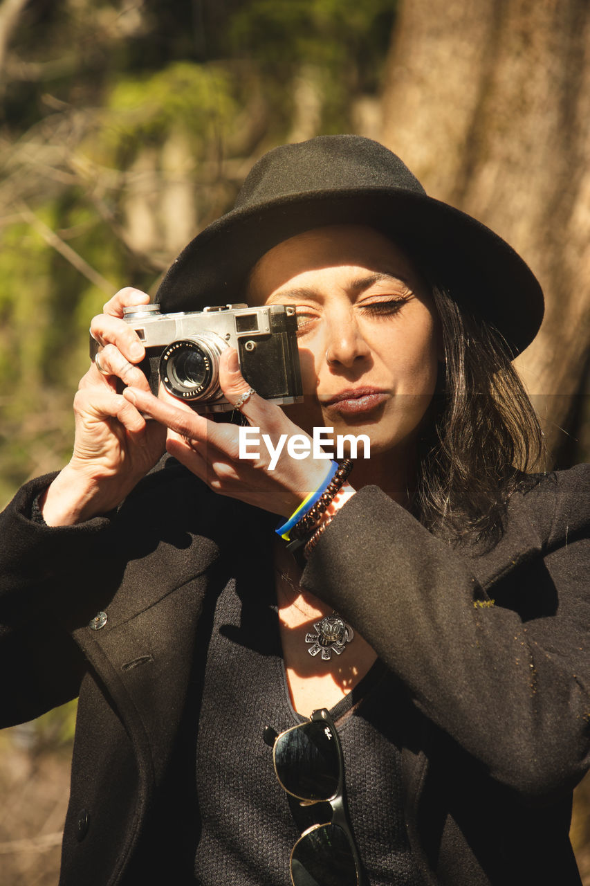 PORTRAIT OF WOMAN HOLDING CAMERA