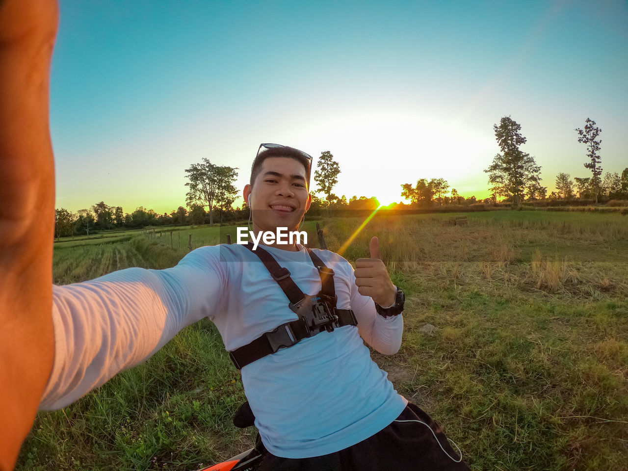 Portrait of smiling man on land against sky during sunset