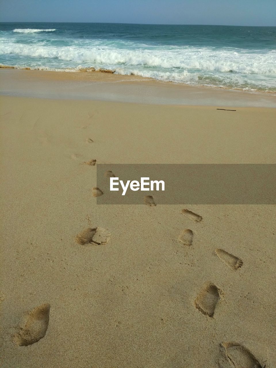 Footprints on sand at beach against sky