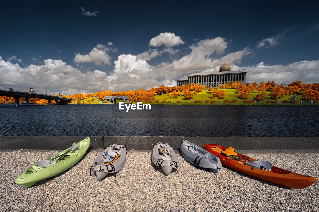 Canoes at lakeshore against sky in city during autumn