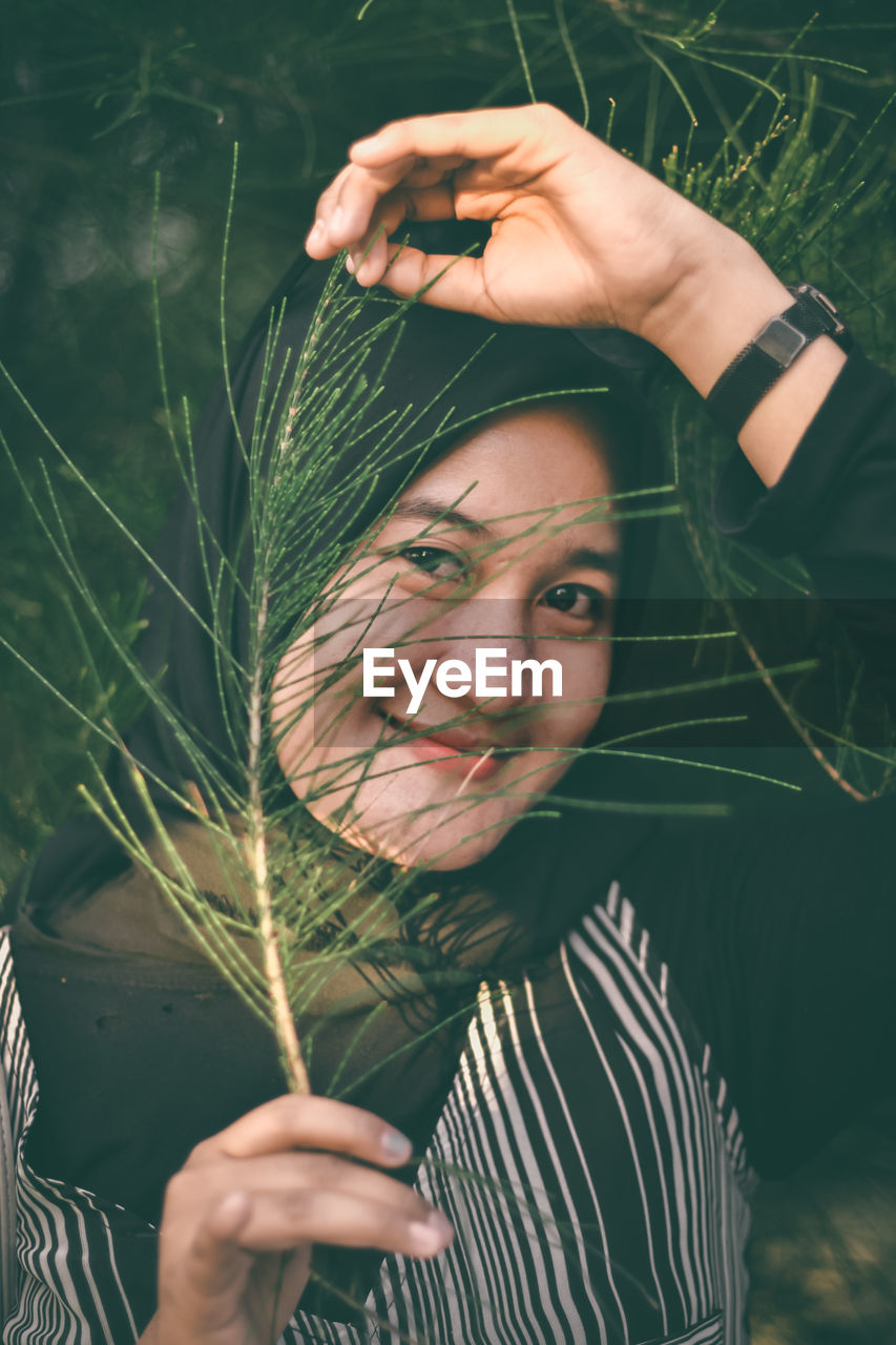 Portrait of young woman holding plant