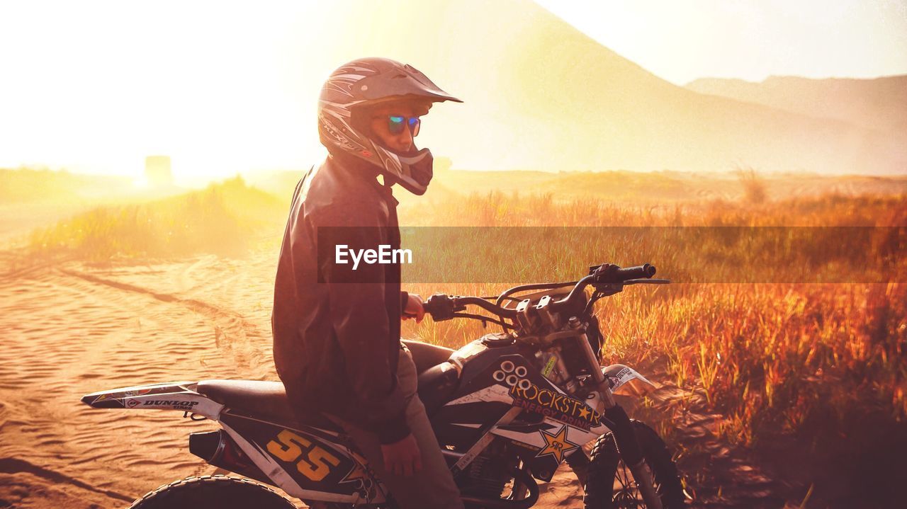 SIDE VIEW OF WOMAN RIDING MOTORCYCLE ON FIELD