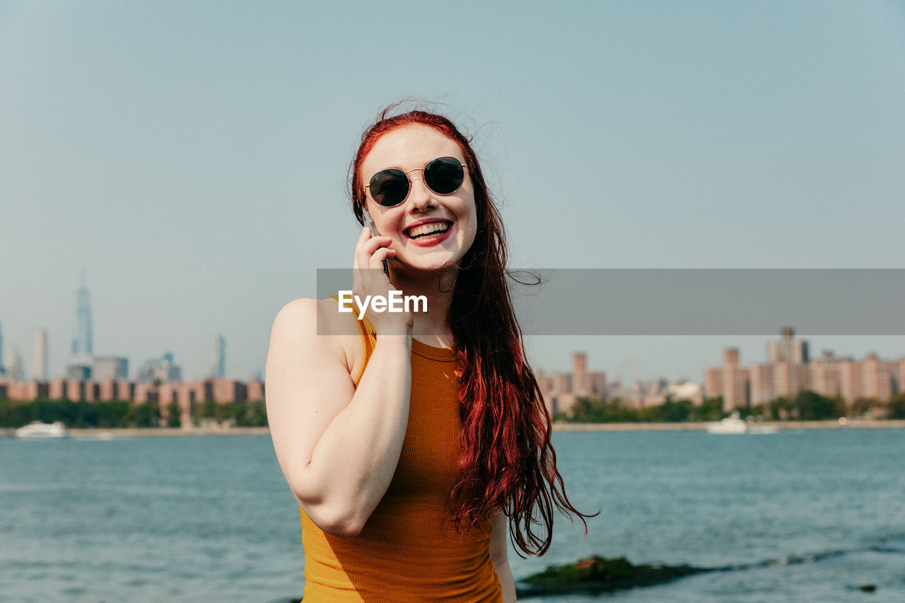 Young woman talking on phone by waterfront.