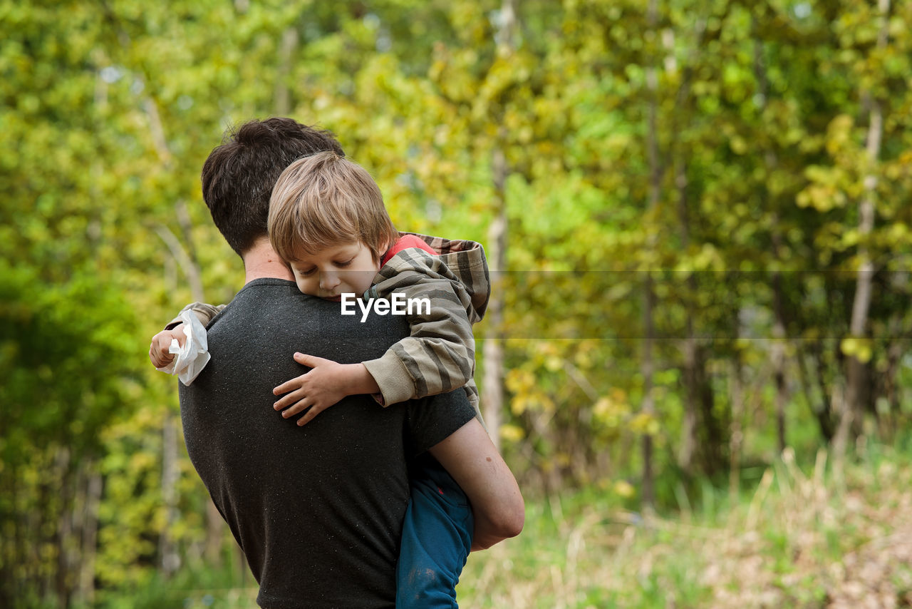 Preschooler boy fell off his bike and crying in dad's arms. father and son