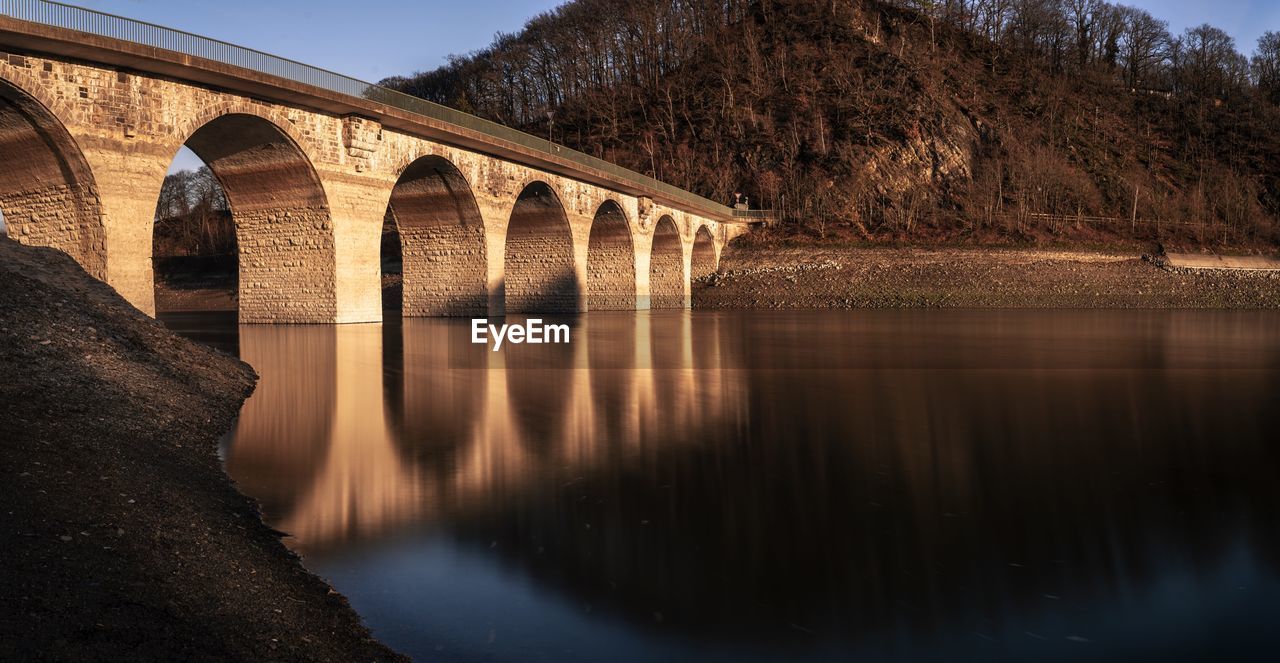 Arch bridge over river against sky