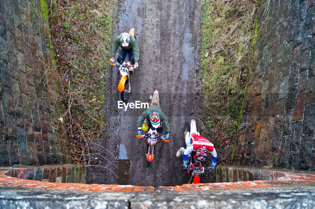 Directly above shot of men riding dirt bikes while entering tunnel