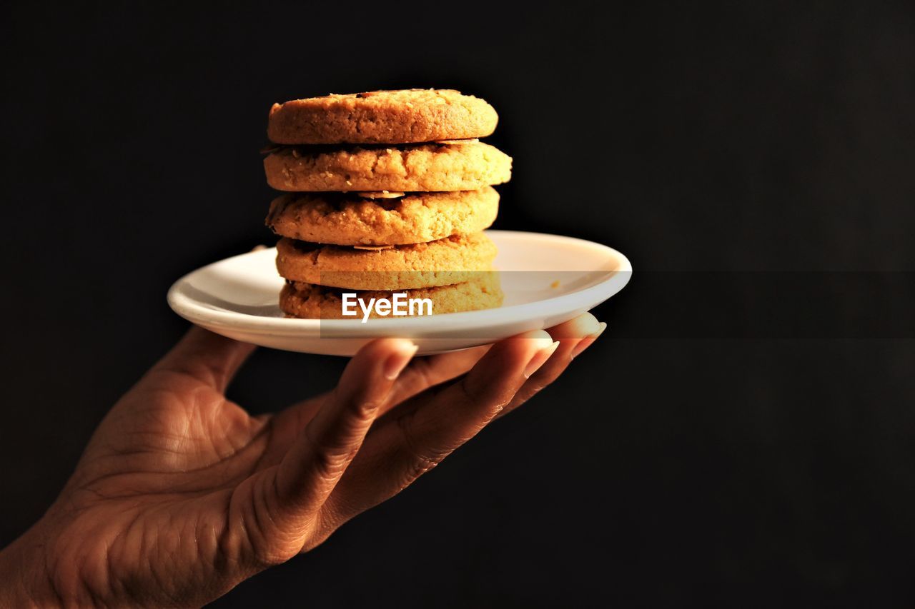 Hand holding cookies plate. stock photo on black background copy space