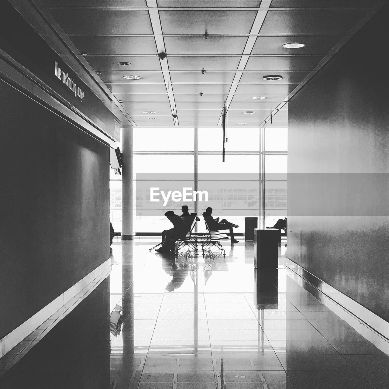 People sitting on chair seen through corridor