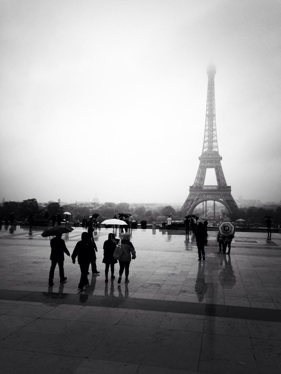 People by eiffel tower against sky during rainy season